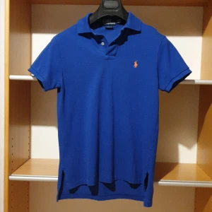 Blå pikétröja från Ralph Lauren - Klarblå pikétröja från Ralph Lauren i passform custom fit.