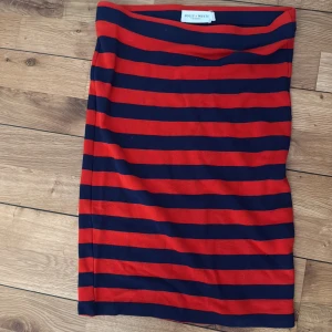 Randig kjol från Holly & White - Snygg kortkjol från Holly & White med breda marinblå och röda ränder. Kjolen har en rak passform. 