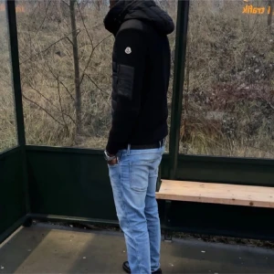Moncler cardigan  - Säljer en svart cardigan från Moncler med stickade ärmar och vadderad front. Jackan har dragkedja, fickor med tryckknappar och en extra ficka med dragkedja på ärmen. Klassisk Moncler-logga på ärmen och snygg, modern look.
