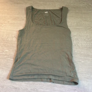 Grön linnetopp från 157, storlek S - Enkel och stilren grön linnetopp från 157 i storlek S. Toppen är ärmlös med rundad halsringning och tillverkad i mjuk bomull med lite stretch för extra komfort. Perfekt att matcha med jeans eller shorts för en avslappnad look.