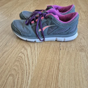 Grå och lila sneakers med rosa detaljer - Snygga sneakers från Bagheera i grått med lila snören och foder samt rosa detaljer på sidorna och snörningen. Ovandelen är i mesh och syntet för bra andningsförmåga. Perfekta för dig som gillar sportig stil och vill ha bekväma skor till vardagen.