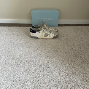 Philippe Model vita sneakers med grå detaljer - Snygga vita Philippe model skor med gula detaljer på snörena och loggan, använda ett antal gånger men har fortfarande mycket att ge skick runt 7/10 kan gå ner lite i priset. Skriv om frågor