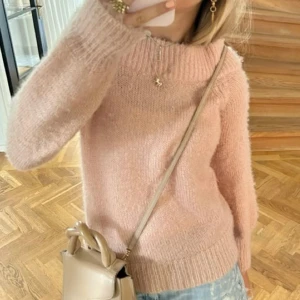 Rosa stickad tröja - Mysig rosa stickad tröja med hög krage och långa ärmar. Perfekt för kyliga dagar och ger en stilren look. Passar bra till jeans eller kjol för en avslappnad stil.