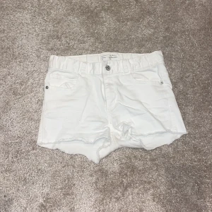 Vita jeansshorts från I dig denim - Snygga vita jeansshorts från I dig denim, modell Savannah Shorts. De har råa kanter nertill, klassisk femficksdesign och knapp- samt dragkedjestängning. Perfekta för varma dagar och ger en fräsch look till din outfit.