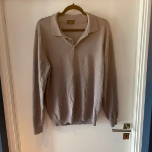 Beige pikétröja från Massimo Dutti - Snygg beige pikétröja från Massimo Dutti med klassisk krage och knappar framtill. Långärmad modell i mjukt bomullsmaterial, perfekt för en clean och stilren look. Nypris på cirka 1200kr😊