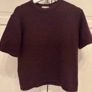 vinröd stickad tröja Gina Tricot - En enkel och stilren trekvartärmad stickad tröja från Gina Tricot. Tröjan har korta ärmar, rund halsringning och en rak passform. Perfekt att styla med jeans eller kjol för en chill look.