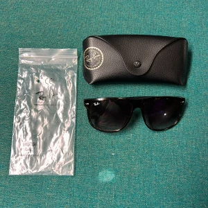 Ray-Ban boyfriends - Snygga Ray-Ban Wayfarer solglasögon med brunmelerad båge och svarta glas. Klassisk fyrkantig form och diskret Ray-Ban-logga på linsen. Kommer med originalfodral och plastpåse. Perfekta för att lyfta din stil i solen.