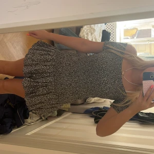 Svartvit blommig klänning från H&M - !!Supersöt svartvit kortklänning från H&M med små blommor, smockad överdel och volang nertill. Klänningen har korta ärmar och en figurnära passform upptill. Perfekt för vår och sommar! Jag kommer inte sänka originalpriset