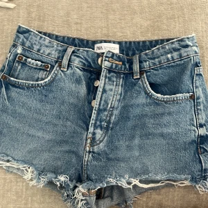 Blå jeansshorts från Zara - Säljer dessa blåa jeans shorts fårn zara mid waist i storlek 36. Använda men fortfarande i bra skick💓