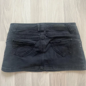 Mini jeanskjol  - En snygg, svart och kort jeanskjol från Terranova.  Kjolen har en knapp och dragkedja framtill. Skriv om ni undrar något! Den är i storlek S men passar även XS