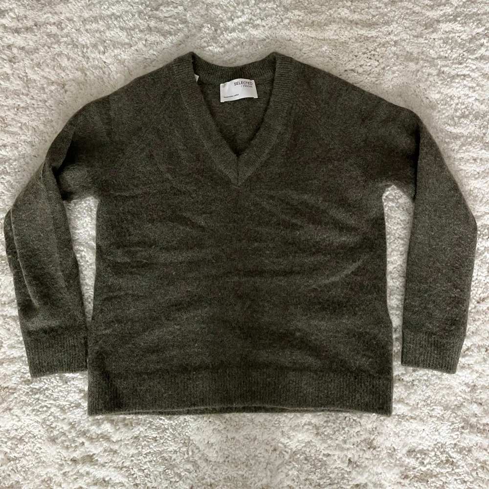 Säljer en stilren grön tröja från Selected Femme i mjuk ull. Tröjan har en v-ringad design och långa ärmar, perfekt för kyligare dagar. Den är både bekväm och snygg, ett måste i garderoben! 🍃. Neuletakit & Villapaidat.