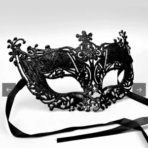 Svart glittrig maskeradmask - Elegant svart maskeradmask med glittrig yta och intrikata detaljer. Perfekt för maskeradbal eller fest. Masken har svarta band för att knytas runt huvudet. Aldrig använd