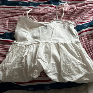 Vit linnetopp från H&M Divided - Säljer en söt vit linnetopp från H&M Divided. Toppen har smala axelband och en volangdetalj nedtill som ger en luftig känsla. Perfekt för varma sommardagar! 🌞