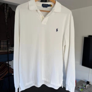 Vit pikétröja från Ralph Lauren - Säljer en klassisk vit pikétröja från Ralph Lauren med lång ärm och den ikoniska loggan broderad på bröstet. Använd en gång. Nypris 1499kr