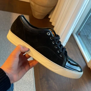 Svarta sneakers från Lanvin (nyskick) - Snygga svarta sneakers från Lanvin med en stilren design. Skorna är i nyskick och är använda fåtal gånger. Köpta från care of Carl för 5000kr ✅Skorna har en blank tå och snörning framtill. Perfekta för en trendig look. Pris 3200! 😀Går att diskutera vid snabb affär. Skorna har bara en deffekt skriv om ni vill se