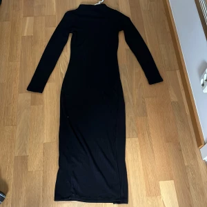 Svart långklänning från Divided - Snygg svart långklänning från H&M Divided med långärmad design. Klänningen har en ribbad struktur som ger en stilren look. Perfekt för en elegant och sofistikerad stil. 