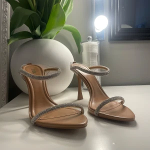 Beige klackskor med glitter Zara - Beige klackskor från Zara med glittrande strassdetaljer på remmarna. Endast använda en gång på bal.
