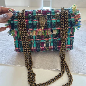 UNIK Kurt Geiger väska  - Säljer en superfin axelväska från Kurt Geiger med ett färgglatt rutigt mönster. Väskan har en kedja i metall och en dekorativ detalj på framsidan. Köpte den i London i vintras  och väskor som denna säljs inte längre så väldigt unik 💥💋