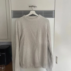Beige stickad tröja från Dobber - Säljer en stilren beige stickad tröja från Dobber. Tröjan har en rund halsringning och långa ärmar med ribbade muddar vid ärmslut och nederkant. Perfekt för kyligare dagar! Köpt från mq för 700kr