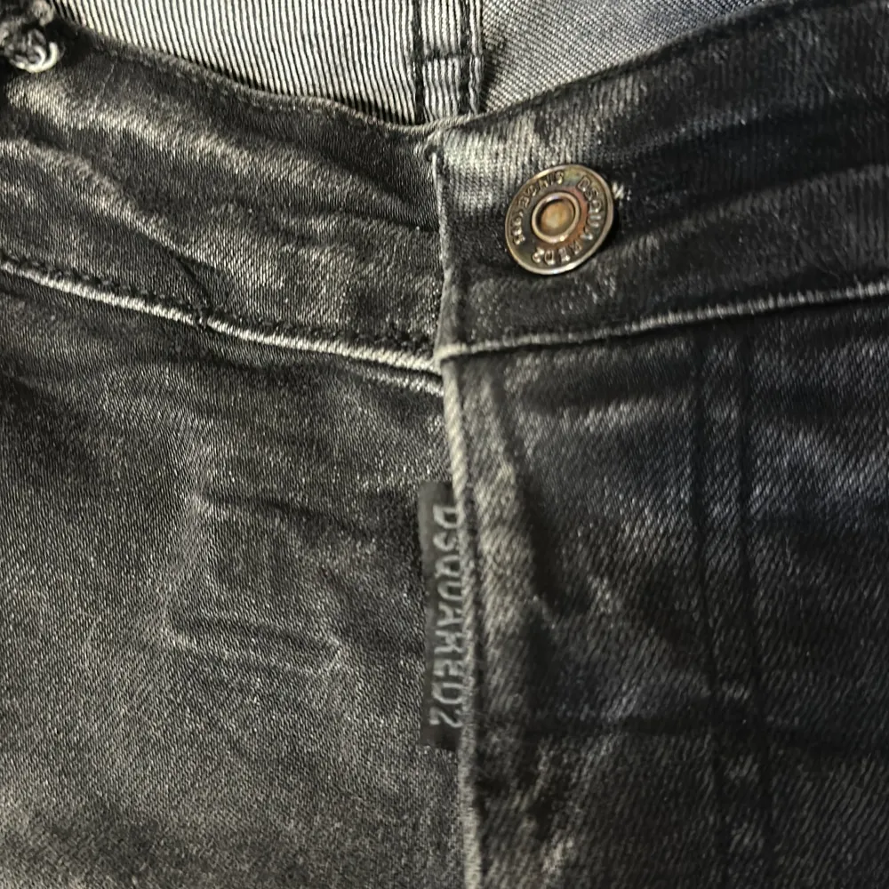 Snygga svarta jeans från Dsquared2 med slitna detaljer och en cool tvättad look. De har en klassisk femficksdesign och knappgylf. Perfekta för en trendig och avslappnad stil.. Farkut & Housut.