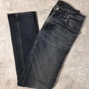 Nudie Jeans - Snygga jeans från Nudie med en klassisk femficksdesign. De har en diskret tvättad look och är perfekta för en avslappnad stil. Passformen är straight och de har en knappgylf. Skick: (7/10) Enda direkten är att det har två hål i innerfickorna. Stolek: W31 L32
