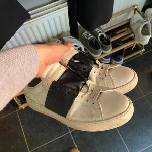 Valentino opens - Snygga sneakers i svart och vitt med en bred svart rem över snörningen. Perfekta för en stilren look. De har en klassisk design med rund tå och platt sula. Bra skick behöva tvättas men det kan lösas enkelt