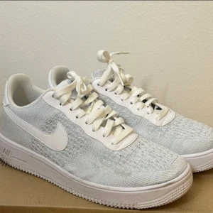 Vita Nike Air Force sneakers - Snygga vita Nike Air Force sneakers med stickad ovandel och klassisk snörning. Perfekta för en stilren look.