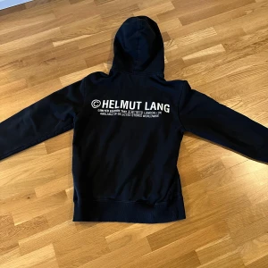 Svart hoodie från Helmut Lang - Säljer en stilren svart hoodie från Helmut Lang med tryck på baksidan| hoodien är använd 3-5 gånger och egentligen inga tecken på användning| nypris ligger på ca 2899!|  Pris kan förhandlas.