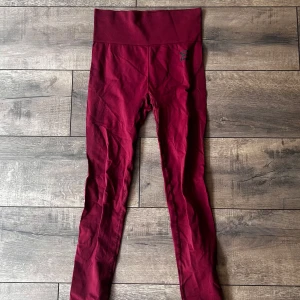 Vinröda seamless tights från Better Bodies - Säljer ett par vinröda seamless tights från Better Bodies. De har hög midja och är tillverkade i ett stretchigt material som passar perfekt för träning. Snygga detaljer längs sidorna och diskret logga på höften.