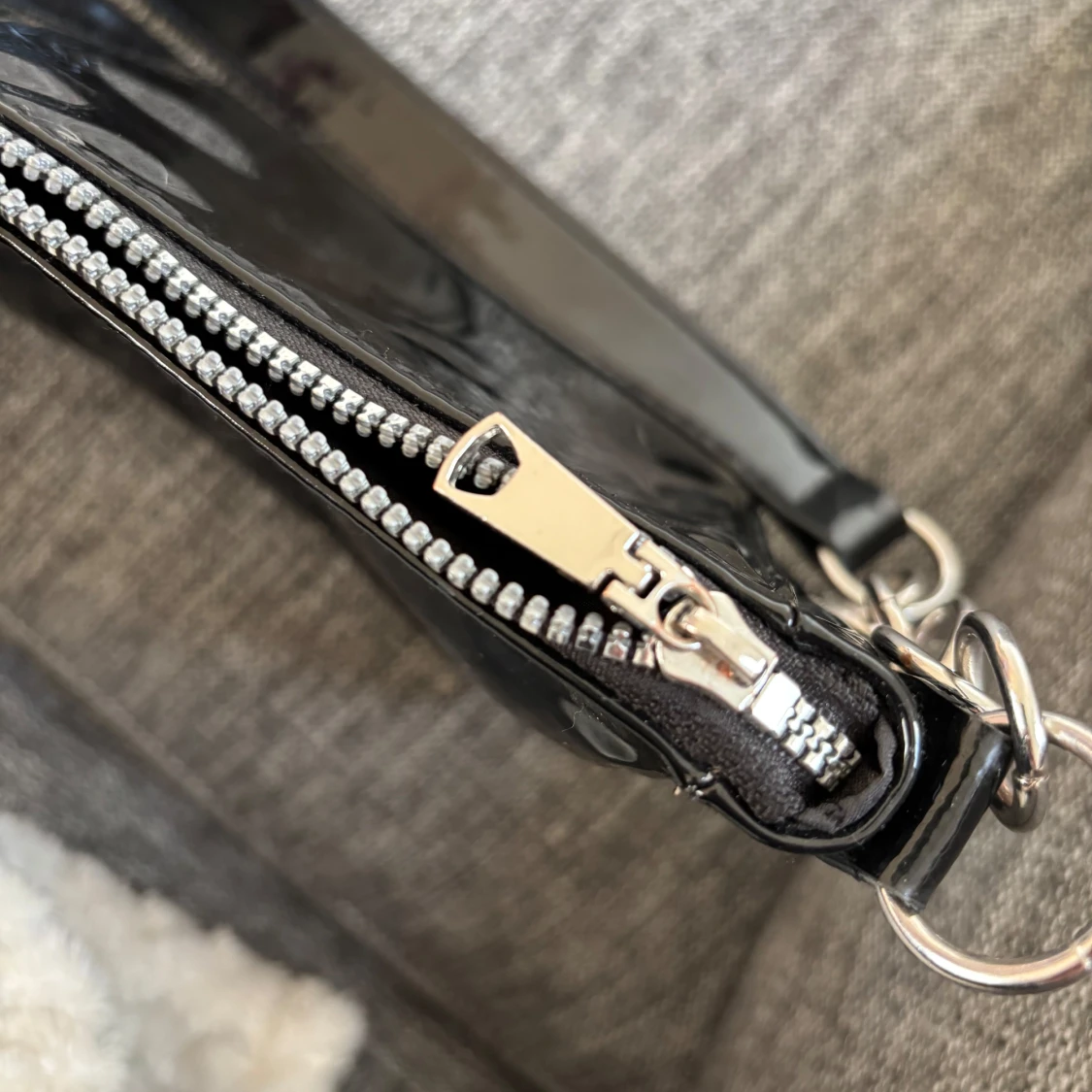 Svart axelväska med kedjedetaljer. Material:lack.  