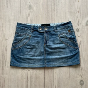 Blå lågmidjad jeanskjol  - Ljusblå lågmidjad jeanskjol från Pulz i storlek M. Fint skick. Passar mig som brukar ha både S och M så skulle säga att den även passar S. Tvärs över midjan är det 41 cm och den är 32 cm lång. Använd gärna köp nu!