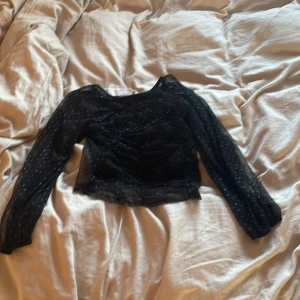 Svart prickig topp från Zara - Säljer en svart topp från Zara med små glitter prickar. Toppen har långa ärmar och en lätt transparent look. Perfekt för en stilren och trendig outfit. 🖤