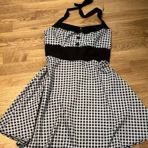 Rutig haltertop klänning  - En dunder söt haltertop klänning i svart, grå o vita färger. Den e i storlek XXL men går säkert att anpassa genom att sy den. Knappt använd.