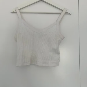 Ribbat linne - Ett vitt ribbat linne från pieces. Lite v-ringad i bysten och kortare i modellen. Fint skick, storlek M. 20kr