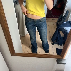 Lågmidjade bootcut jeans wrangler - Snygga blå jeans med bootcut-stil och låg midja.  Klassisk design med fem fickor och dragkedja. Passar 36-38