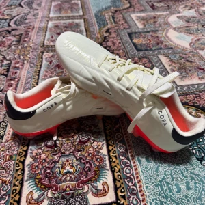 Adidas Copa Pure Elite fotbollsskor i vitt och neonrött - Säljer ett par Adidas Copa fotbollsskor i vitt med neonröda detaljer och svarta neonröda. Helt nya och oanvända, fick de från en vän man är liten för mig,  skruv dobbar men går att ta av, pris kan diskuteras och fler bilder kan skickas vid intresse. Storlek 40,5 och passar perfekt för 40.