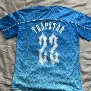 Äkta Trapstar T-Shirt Oversized - Säljer en blå kortärmad tröja från Trapstar med ett unikt mönster. Tröjan är oversized och passar nog M och L bäst. Står S på taggen men har tagit kontakt och det blev bara tryckfel. Använd 3 gånger så den är som ny