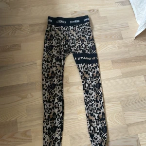 Leopardmönstrade träningstights från Stronger - Säljer ett par snygga leopardmönstrade träningstights från Stronger i storlek S. Tightsen har svart resår i midjan. Den har ett pyttelitet hål på knät som man kan se på bild fyra annars är dem jättefina. Pris kan diskuteras