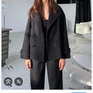 Svart kappa med knappar - Snygg svart kappa med dubbelknäppning. Jackan har en lös passform och långa ärmar med knappar vid ärmsluten. I strl xs/s och finns inga defekter❣️