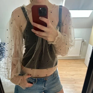 Beige meshblus med svarta prickar - Säljer en transparent beige meshblus med svarta prickar och puffiga långärmar. 