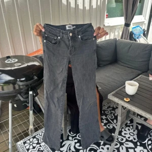 Grå bootcut jeans med fickdetaljer - Snygga grå jeans med bootcut passform och coola fickor med lock och knapp bak. Klassisk femficksmodell framtill och silverfärgade knappar. Perfekta för dig som gillar en avslappnad men trendig stil.