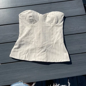 Randig korsettopp från Bershka XS - Supersnygg vit/krämfärgad korsettopp från Bershka i storlek XS. Säljer då den tyvärr var förliten och jag glömt skicka tillbaka, helt ny med prislapp kvar!