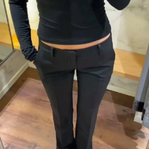 Svarta bootcut kostymbyxor  - Snygga svarta kostymbyxor med låg midja Byxorna har klassiska fickor fram, hällor för bälte och stängs med dragkedja och knapp. Perfekta för en clean och stilren look. Fråga gärna efter fler bilder🙌 stl 36 eller S obs är uppsprättade längst ner