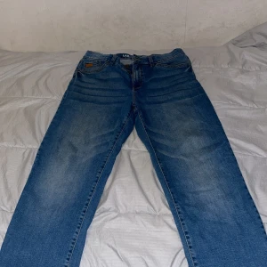 Baggy jeans från LAB Industries - Säljer ett par blå baggy jeans från LAB Industries i loose fit-modell. Jeansen har klassisk femficksdesign, snygga slitningar och är gjorda i hållbar denim. Perfekta för dig som gillar en avslappnad och trendig stil.