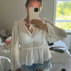 Vit prickig blus från Zara med knyt - Supersöt vit blus från Zara med diskreta prickar, knytband vid halsen och knappar framtill. Långa, luftiga ärmar med volangig nederkant och knyt vid handlederna. 🌸🌸