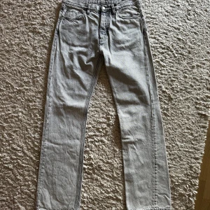 Grå raka jeans från HOPE, strl 29 - Snygga ljusgrå jeans från HOPE i modellen Rush Jeans. Klassisk femficksdesign, raka ben och normal passform. Jeansen är tillverkade i bomull och har en stilren look med diskreta sömmar. Perfekta för dig som gillar minimalistisk och clean stil.