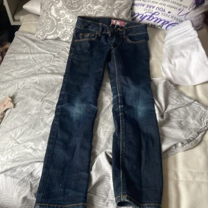 Mörkblå jeansbyxor med raka ben - Snygga mörkblå jeans med klassiska kontrastsömmar och raka ben. Byxorna har fem fickor, bälteshällor och läderpatch bak i midjan. Jeansen är i ett robust denimtyg och har en tidlös look som passar till det mesta.