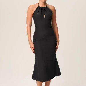 Adoore BYTES/SÄLJS - Rozzano midiklänning. Den här klänningen har en halterneckringning med ett droppformat utskärningsdetalj, kompletterat med ros- och plisserade detaljer. Den öppna ryggen, timglassilhuetten och slitsen baktill skapar en elegant look för alla tillfällen. Klänningen är helfodrad och har en dold dragkedja i ryggen. Helt ny med lapparna kvar!❤️ Mötes upp och bytes mot en annan modell adoore i storlek 36. Eller säljs! ❤️‼️till anklarna på mig som är 160.