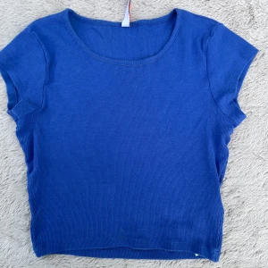 Blå ribbad topp från FB Sister - En enkel och stilren blå ribbad topp från FB Sister. Modellen har rund halsringning och korta ärmar, perfekt för en avslappnad look. Toppens material är mjukt och stretchigt, vilket gör den bekväm att bära hela dagen.