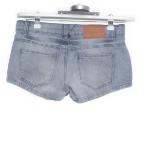 Ljusblå jeansshorts från Only - Snygga ljusblå lågmidjade jeansshorts från Only med klassisk femficksdesign och bälteshällor. Modellen är kort och har knapp- och dragkedjestängning framtill. Perfekta för varma dagar.